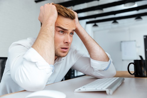 graphicstock upset disappointed young businessman sitting at workplace with hands on head HdVZiizr2e