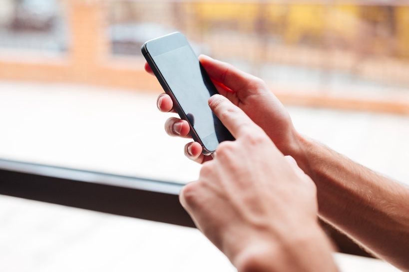 man kijkt op smartphone om zijn telefoonnummer naar zijn date te sturen