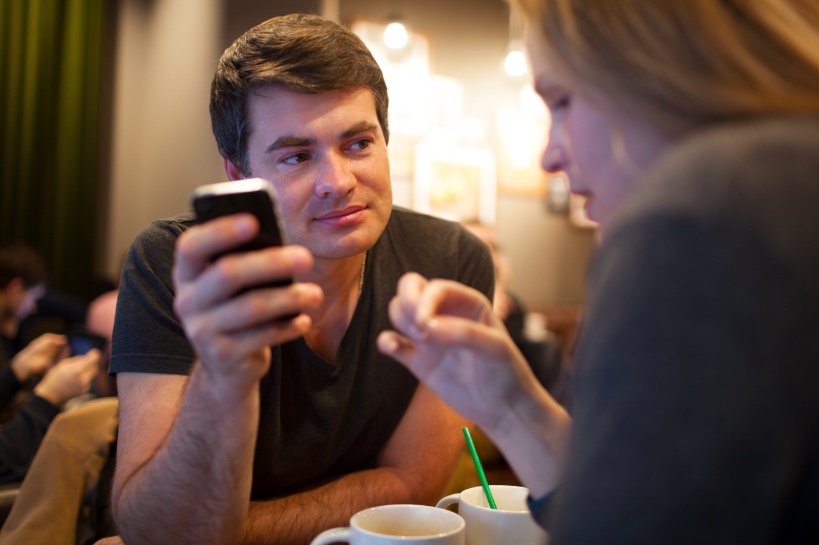 man kijkt op telefoon tijdens date omdat hij geen interesse in vrouw heeft