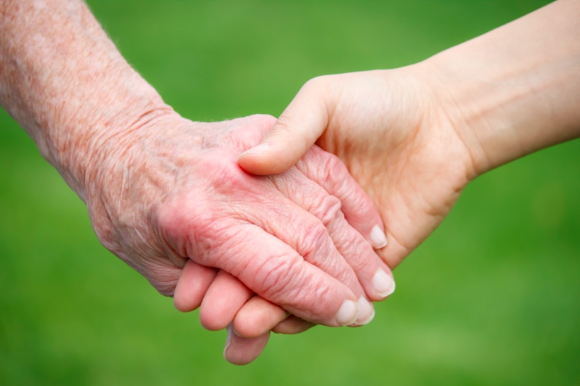 oudere man en veel jongere vrouw houden elkaars hand vast