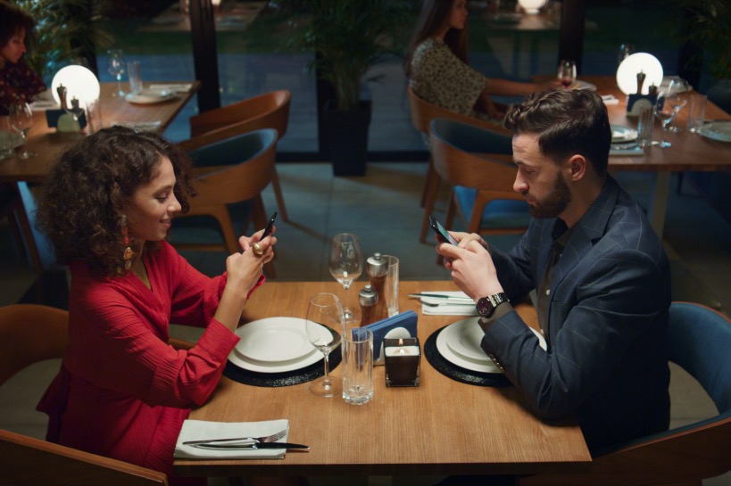 stel zit op eerste date beide op telefoon