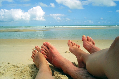 voeten van een stelletje op het strand tijdens hun vakantie samen