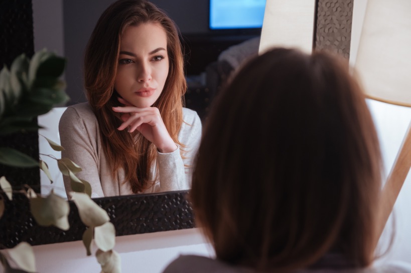 vrouw bekijkt zichzelf in spiegel