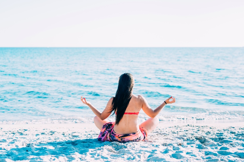vrouw mediteert op strand om open minded te worden