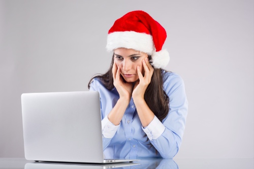 vrouw met kerstmuts zit verdrietig naar profielen op datingsites te kijken