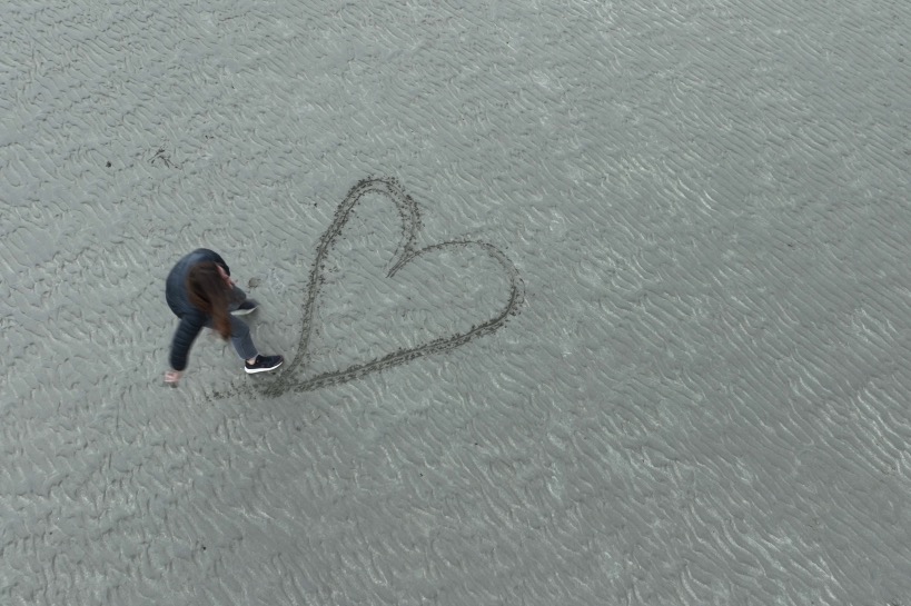 vrouw tekent hart in het zand voor haar vakantieliefde