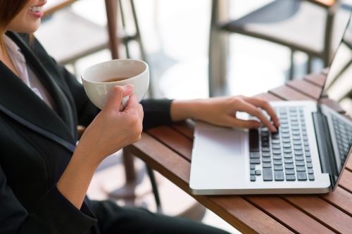 vrouw zit lachend achter haar laptop op zoek naar haar nieuwe liefde