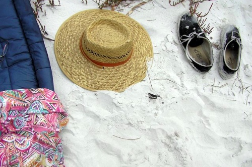 zonnehoed en schoenen in het zand om de rust van een vakantie in je eentje uit te beelden